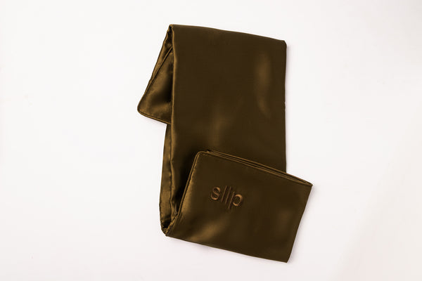 Folded brown silk pillowcase with slip embroidery on a white background