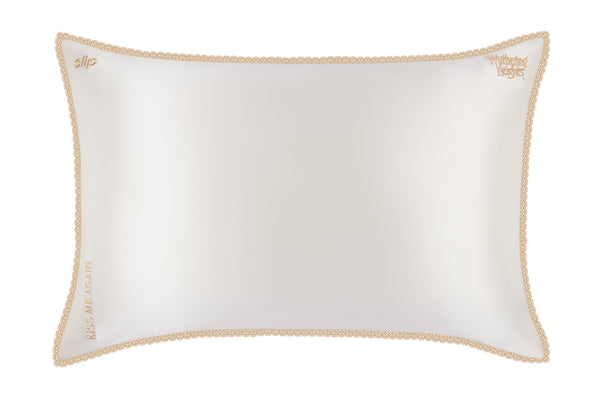 White pillow with gold lace trim on a white background