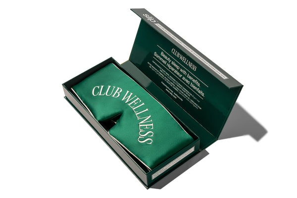 Green box containing a 'Club Wellness' blockout sleep mask, with slip branding on a white background